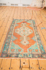 Distressed pile, fringed edge, and mint green spandrel of a vintage Oushak rug corner.
