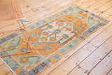Distressed Oushak rug corner with faded tangerine, mint, and slate blue primitive floral design.