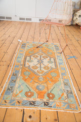 Distressed Turkish Oushak rug with primitive medallion and floral palmettes in faded tangerine, mint, and slate blue.