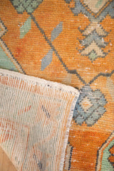 Distressed vintage Oushak rug with faded tangerine pile, mint accents, and hand-knotted reverse.