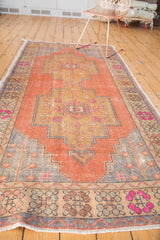 Distressed pile texture of vintage Oushak, apricot field, grey spandrel, bright pink border flowers.