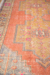 Distressed pale orange apricot Oushak rug section with dusty gold patterns and hot pink florals.