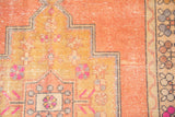 Distressed vintage Oushak carpet detail with apricot field, gold spandrel, and hot pink blossoms.