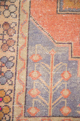 Distressed Oushak carpet detail showing blue-grey field with apricot germinating plant and weeping willow motifs.