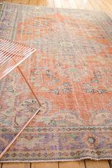 Faded apricot distressed Oushak rug corner showing rococo border motifs and soft pistachio green.