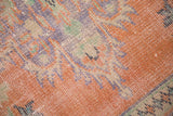 Distressed Oushak rug pile with time-softened tangerine, blue, and green tones.