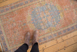 Distressed vintage Oushak runner pile, featuring faded dusty grapefruit red and pale royal blue floral motifs.