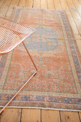 Worn dusty grapefruit red field, pale blue floral motifs on distressed Oushak runner.