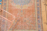 Distressed texture in dusty grapefruit red and pale blue floral patterns on Oushak rug.