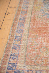 Distressed dusty grapefruit red Oushak runner with even wear and secured blue border.