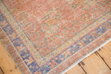 Worn pile texture of a distressed vintage Oushak rug with faded grapefruit red and blue.
