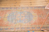 Distressed Oushak runner showing faded grapefruit red and pale blue with visible foundation.