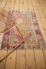 Distressed vintage Oushak rug, showing worn pile texture, bright pink, and dusty gold tones.