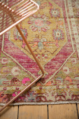 Corner of distressed vintage Oushak rug, with bright pink spandrel and dusty gold field.