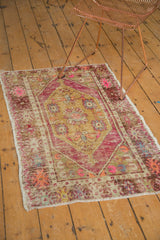 Textured distressed Oushak rug featuring bright pink, dusty gold, and ivory oblong medallion.
