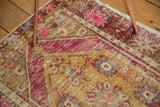 Distressed vintage Oushak rug showing its textured pile, dusty gold medallion, and bright pink motifs.