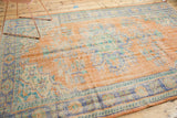 Distressed Oushak rug showing light foundation through pale apricot and faded blue florals.
