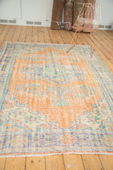 Distressed vintage Oushak carpet pile showcasing even wear, light foundation, apricot, blue, and mint green.