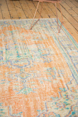 Distressed Oushak rug pile texture with faded apricot, dusty blue, and visible foundation.