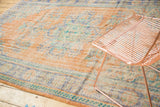Distressed Oushak rug with faded apricot, dusty royal blue, and mint green floral motifs.