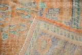 Worn vintage Oushak rug pile in apricot, blue, ivory, showing foundation and original side cord.