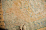 Distressed vintage Oushak rug detail, faded apricot, ivory, and mint green, showing textured wear.