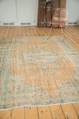Vintage Turkish Oushak carpet with distressed apricot field and visible foundation.
