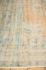 Close-up of distressed vintage Oushak rug with worn pile, exposed foundation, and soft colors.