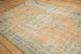 Distressed vintage Oushak rug detail: faded apricot field, visible foundation, soft mint florals.