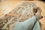 Vintage distressed Oushak runner showcasing worn peach, ivory, and brown stylized geometric patterns.