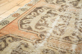 Distressed Oushak rug runner texture, highlighting dusty peach border and faded ivory geometric patterns.