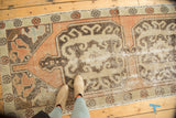 Distressed Oushak runner's central medallion with worn terra cotta and ivory motifs.