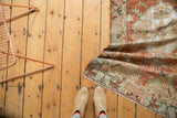 Corner of distressed vintage Oushak runner with cinnabar red, ivory, pale blue, and fringed edge.