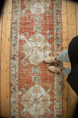 Distressed Oushak runner showcasing pale cinnabar red field, ivory medallion, and sickle leaves.