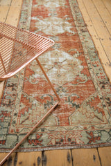 Distressed vintage Oushak runner showing worn cinnabar red field with ivory sickle leaf patterns.