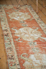Distressed cinnabar red field and intricate ivory border of a vintage Oushak runner.