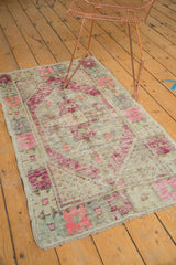 Worn Oushak rug corner, showing bubble gum pink and pale blue geometric florals with ivory fringe.