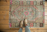 Distressed Oushak rug with a bright pink medallion, pale slate blue field, and primitive floral motifs.
