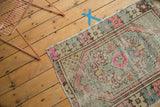 Distressed Oushak rug corner, showing worn pile, dusty pink, silver, pale blue motifs.