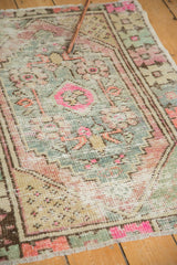 Distressed vintage Oushak rug pile with primitive pink, dusty purple, and blue motifs.