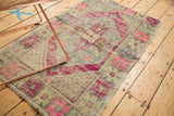 Distressed Oushak rug corner detail, highlighting worn pink, blue geometric floral motifs.