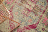 Distressed Oushak rug detail: primitive pink, blue, ivory geometric floral patterns and visible foundation.
