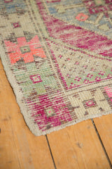 Distressed Oushak rug corner, vibrant magenta motifs, softened pile, and intact side selvage.