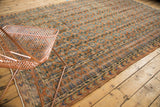 Distressed vintage Oushak rug border showing terra cotta diamonds, blue meandering vine, and floral field.