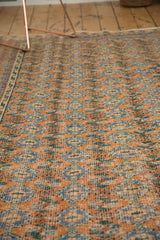Distressed Oushak rug featuring terra cotta rust and blue floral gul motif with border.