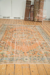 Distressed vintage Oushak rug pile texture showing faded apricot, dusty blue, and mint green.