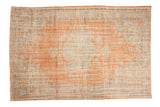 Vintage distressed Oushak rug, pale terra cotta field, faded blue medallion, ivory floral motifs.