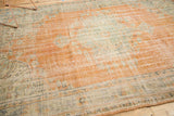 Angled view of a hand-knotted vintage Oushak rug, highlighting distressed pile and faded hues.