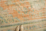 Distressed Oushak carpet, pale terra cotta field with faded floral motifs, visible wear.