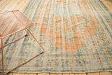 Faded terra cotta, blue-green floral patterns and visible wear on Oushak carpet.